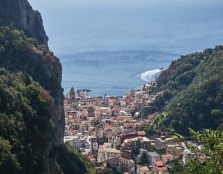 View from the hillside village of Pontone of the red-roofed town of Amalfi below, tumbling down the green slopes to the sea.