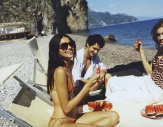 un gruppo di amici mangia anguria sulla spiaggia