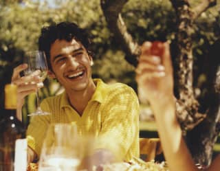 un uomo con un bicchiere di vino in un tavolo in giardino