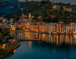 Portofino marina on a Christmas night, lined with glittering waterside restaurants casting reflections on the dark water.