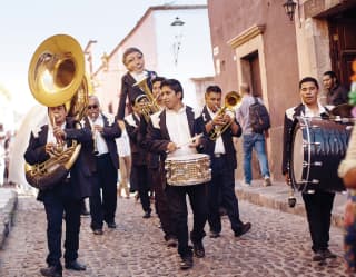 Banda de bronce mexicana paseando por una calle adoquinada