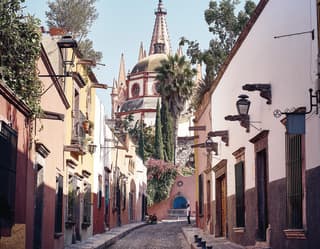 Curved cobblestone street lined with pastel coloured colonial-style homes