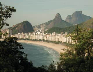 Copacabana beach lined with white high-rises and towering mountains beyond
