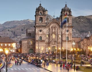 Cusco cathedral at sunset with mountains in the background