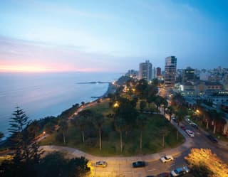 The shoreline of Lima at sunset with the twinkling cityscape beyond