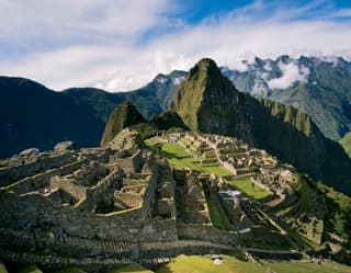 Stunning view of Machu Picchu, cradled in a mountain crest and surrounded by forested peaks towering over the Sacred Valley.