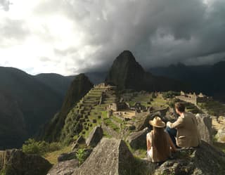 Una pareja sentada admirando la ciudadela de Machu Picchu
