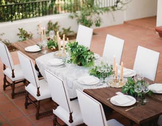 Wedding banquet table on a terrace, with candles and leafy centerpieces