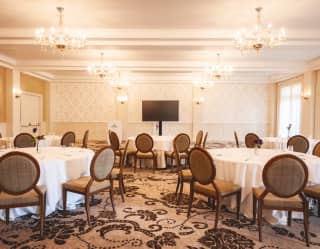 The light and spacious Riviera ballroom arranged for a private business meeting with round tables and video screen