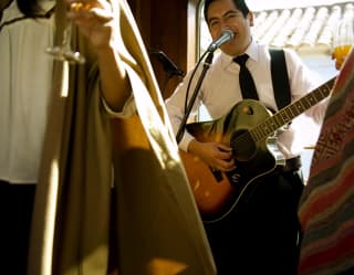 A musician smiling and playing guitar in the Hiram Bingham bar car