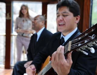 Close-up of a musician with a Spanish guitar accompanying a singer as they provide live entertainment in the observation car.