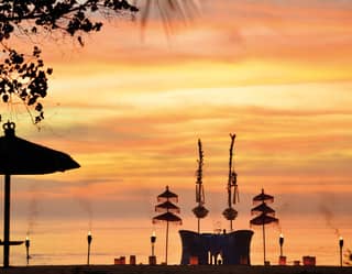 Silhouette of a candlelit table for two the beach against an orange sunset