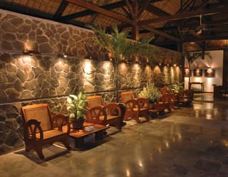 At night the hotel lobby glows, as downlights warm the rich wood of beautifully-carved chairs and gleam on marble tiles.