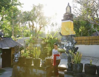 Lady stepping down stone steps from a Balinese statue surrounded by potted palms
