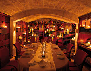 Candle-lit barrel vaulted restaurant room, with table set for private parties