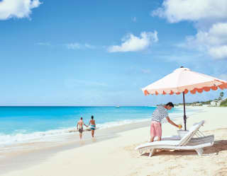 Couple walking along platinum sands in Baie Longue with sun bed in the foreground