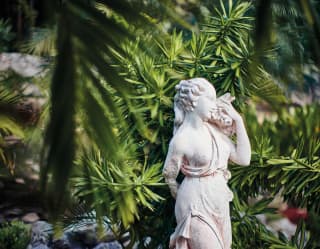 Grecian-style stone statuette among tropical gardens