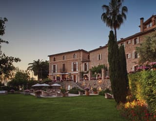 Vast stone-built Spanish villa surrounded by manicured lawns and gardens at sunset