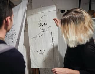 Lady holding up a sewn portrait of a lady on a textile canvas