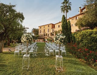 Rows of chairs set either side of an aisle for a wedding in a lush Spanish garden