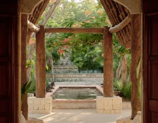 View from the wooden pitched palapa entrance of Ranas Courtyard to the beautiful Mayan-inspired fountain and gardens.