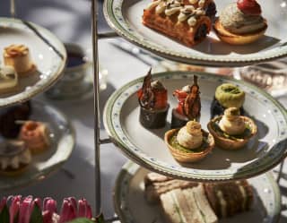 Sandwiches, mushroom tartlets, bobotie sausage rolls and other savoury treats are served on a tiered stand at afternoon tea.