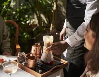 A tea sommelier strains speciality leaves on a tray at the table of guests enjoying Mount Nelson's iconic afternoon tea.