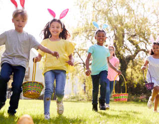 Children wearing bunny ears running with woven baskets