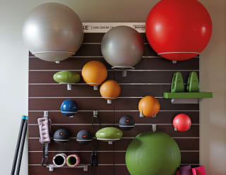 Fitness centre wall shelves with brightly coloured medicine balls and weights