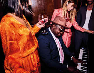 Man playing the piano surrounded by smiling guests at a party