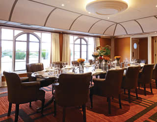 Meeting room with comfy armchair seats around a polished wood table