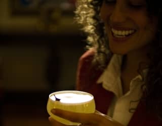 A guest enjoys a freshly mixed cocktail in the historic candlelit lobby bar