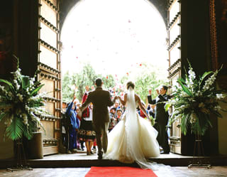 Newly married couple stepping out to applause from a group of guests