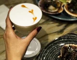 Close up shot of a guest's hand holding a cocktail at the Belo Bar