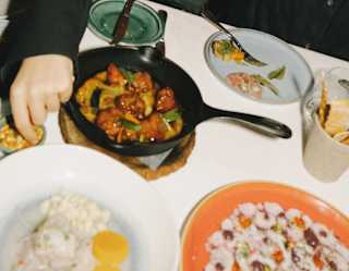 Snapshot of guests enjoying drinks and food at Tragaluz at a table filled with plates of vibrant dishes.