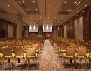 Rows of coral-hued banquet chairs in a large venue with a pink patterned carpet