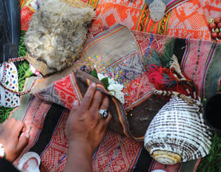 Lady's hands rolling a Peruvian woven blanket topped with shells