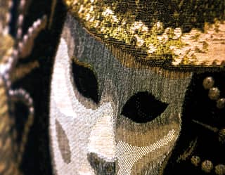 An embroidered representation of a theatre's tragedy mask in white, black, brown and gold