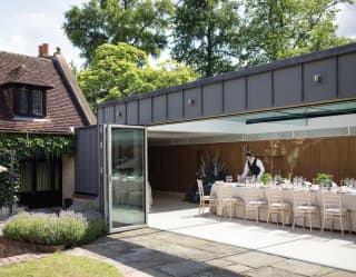 Contemporary glass-walled annex set for a wedding on a sunny day