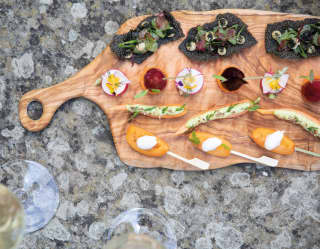Wooden platter with a selection of canapés garnished with edible flowers