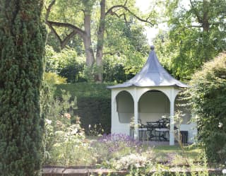Garden pavilion surrounded by tall hedges in a sunny country garden