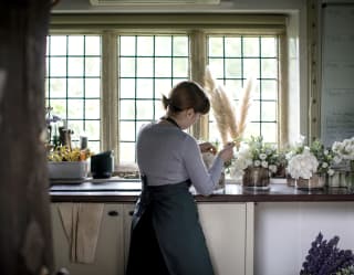 Florist preparing bouquets at a countertop in front of medieval-style windows
