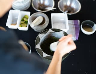 Looking down on a cookery class table as a chef blends a fragrant spice combination with a black and white pestle and mortar.