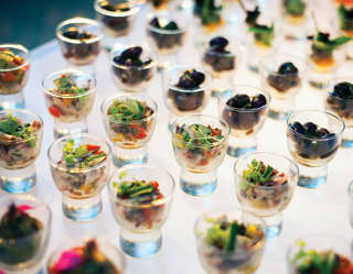 Rows of clear glass egg cups filled with various canapé-style light bites