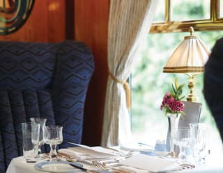 Formal linen-coated dining table on a train with plush armchair seating