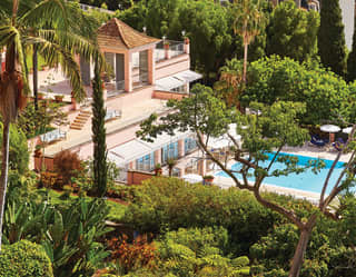 Looking down through hillside Mediterranean-style gardens to the pretty pink of Reid's Palace and a sky-blue swimming pool.