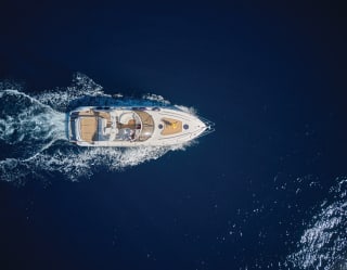 Birds-eye-view of a luxurious small yacht sailing across deep blue waters