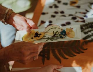 At a botanical workshop, a guest creates a picture using pressed yellow pansies, leaves and ferns from the hotel's gardens.
