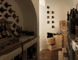 A stack of wine crates sits against the back of the cellar room which has rendered walls with pigeon-holes for wine bottles.