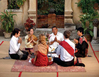 Six people sitting in a circle for a baci ceremony in an oriental courtyard
